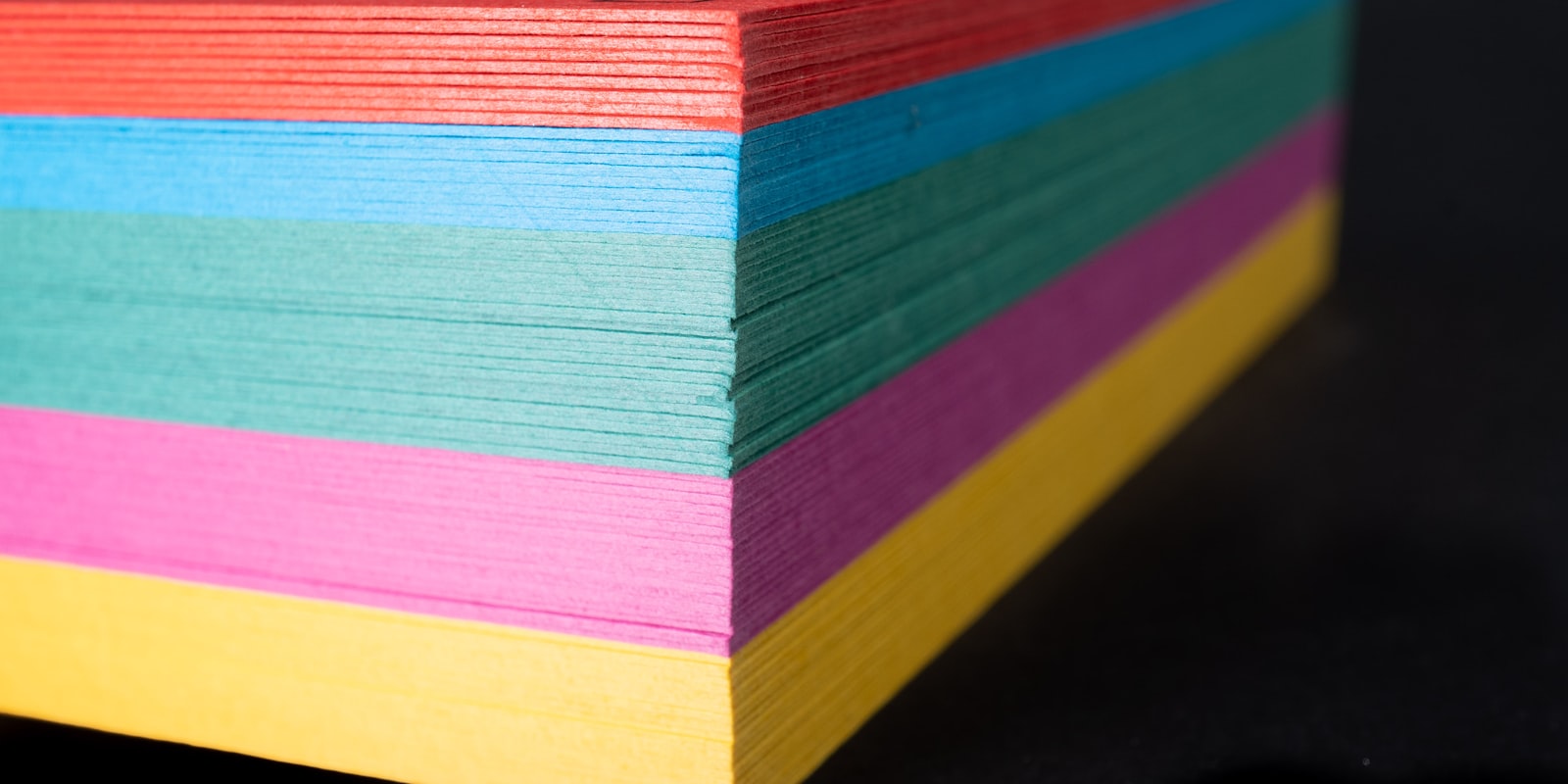Stapel aus buntem Tonpapier in Rot, Blau, Grün, Pink und Gelb
