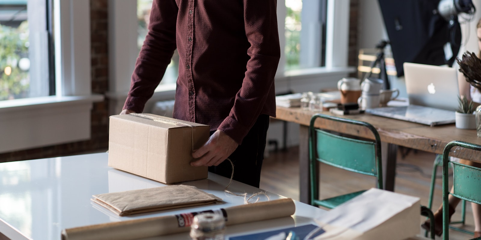 Eine Person verpackt ein Paket an einem hellen Arbeitstisch