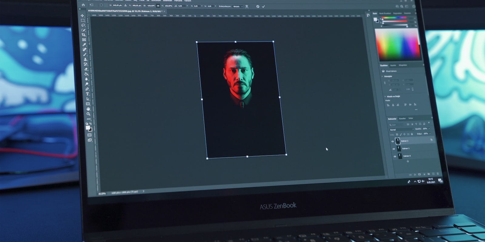 Laptop mit geöffneter Bildbearbeitungssoftware auf einem dunklen Schreibtisch